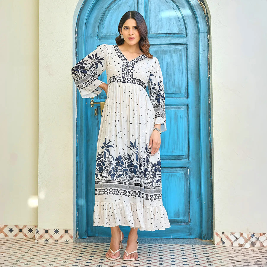 Model wearing a white maxi dress for women with deep navy floral border print, V-neckline, and 3/4 sleeves, standing in a front pose.