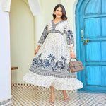 Stylish long maxi dress with navy floral prints, model holding a handbag, adding a chic vacation-ready look.