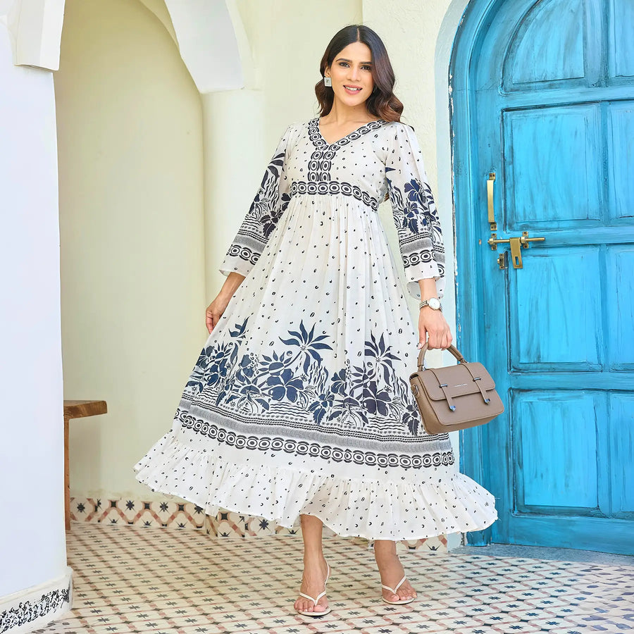 Stylish long maxi dress with navy floral prints, model holding a handbag, adding a chic vacation-ready look.