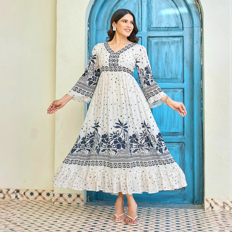 Elegant white maxi dress with navy floral print, V-neck, and flared sleeves, model standing with arms slightly open to showcase the dress flow.