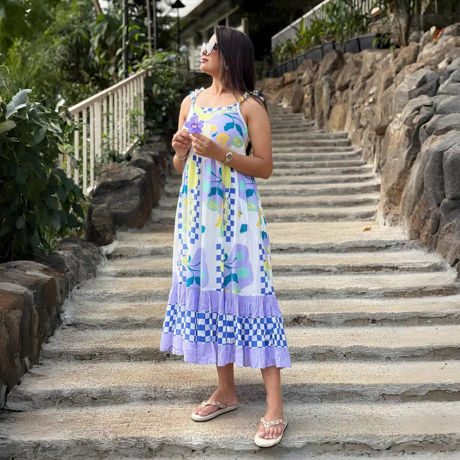 Woman in Sleeveless midi dress for walking on stone steps outdoors, holding a flower.