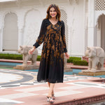Woman in a black floral midi dress walking confidently in a palace courtyard