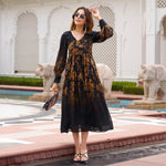 Woman wearing black one piece dress with floral print, holding purse