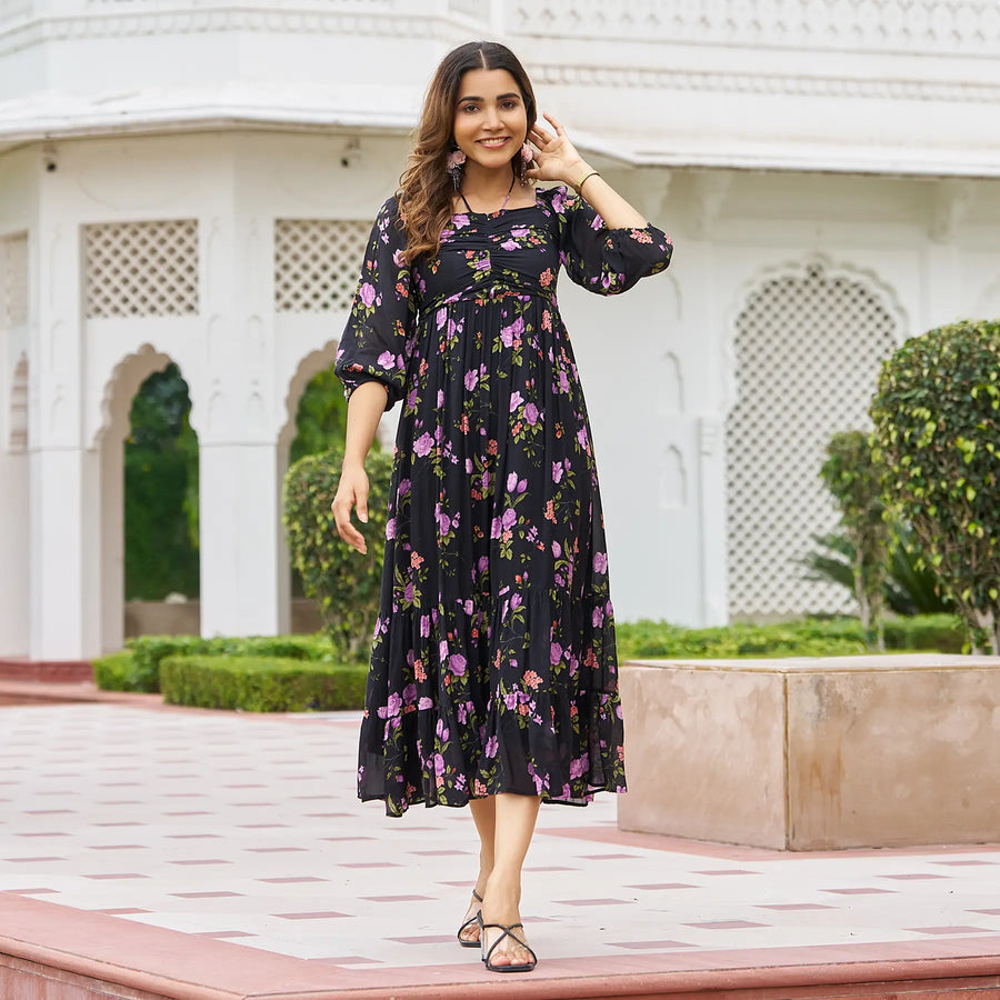 Stylish black floral midi dress for women shown in motion, model smiling and stepping forward.