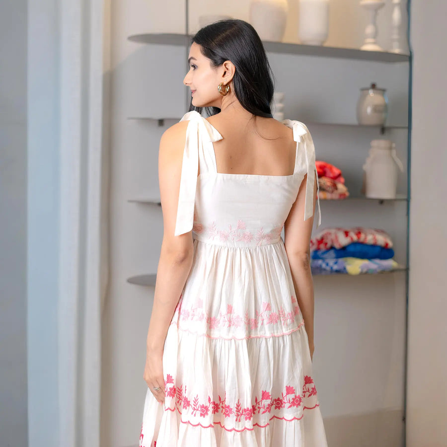 Back view highlighting tie-up straps and embroidery in a chic frock style one piece.