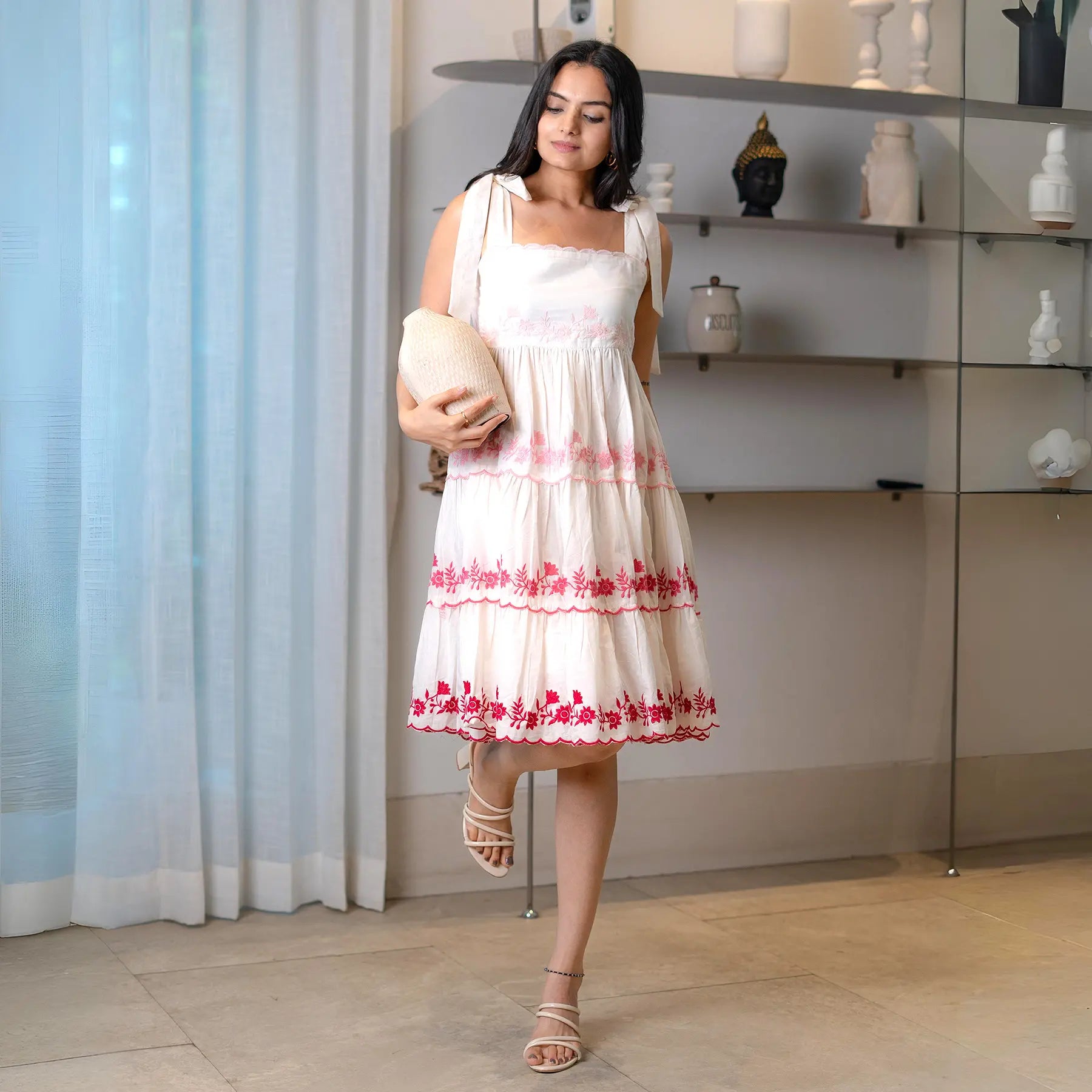 Front pose of an embroidered short frock for women with tie straps and delicate layered design.