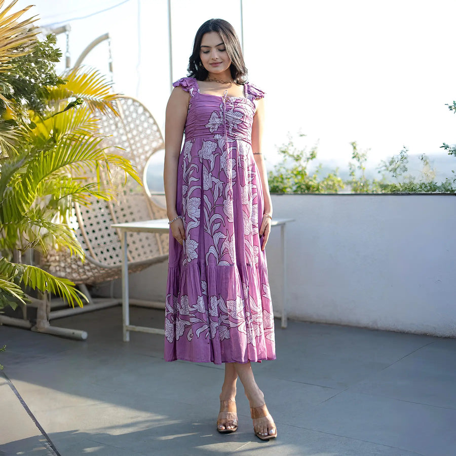 Woman posing in a flowy purple maxi dress with floral design, perfect for summer trips.
