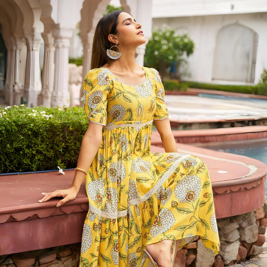 Close-up sitting pose of Marigold Aura yellow midi dresses – ideal for Haldi functions with festive floral charm.