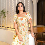 Seated close-up showing neckline and puff sleeves of a floral maxi one piece, perfect for elegant occasions.