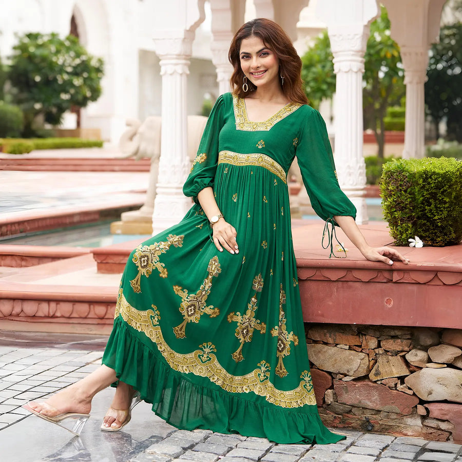 Seated pose in a green long sleeve one piece dress with golden prints, a graceful look for traditional family functions.