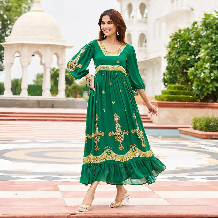 Walking side pose in an emerald green a line maxi dress with gold detailing, styled for festivals and cultural events.