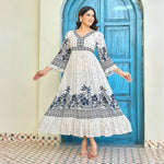 Elegant white maxi dress with navy floral print, V-neck, and flared sleeves, model standing with arms slightly open to showcase the dress flow.