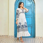Side-view of a white floral maxi dress with border detailing, model smiling and walking, perfect for casual vacation or brunch styling.