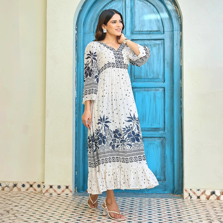 Side-view of a white floral maxi dress with border detailing, model smiling and walking, perfect for casual vacation or brunch styling.