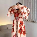 Creative pose focusing on the bell designer sleeves of this floral maxi dress, styled for festive nights.