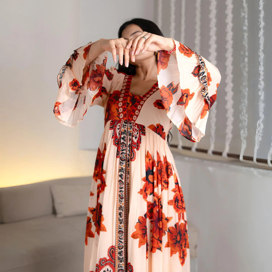 Creative pose focusing on the bell designer sleeves of this floral maxi dress, styled for festive nights.