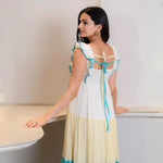 Back view of a long one piece dress with tie detail and breezy silhouette.