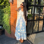 Influencer outdoors in a long floral maxi styled with sunglasses, perfect for travel and resort wear.