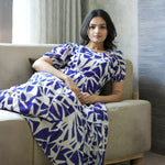 Model sitting gracefully in Abstract print midi dress for women, styled with puff sleeves and lightweight fabric ideal for summer wear.