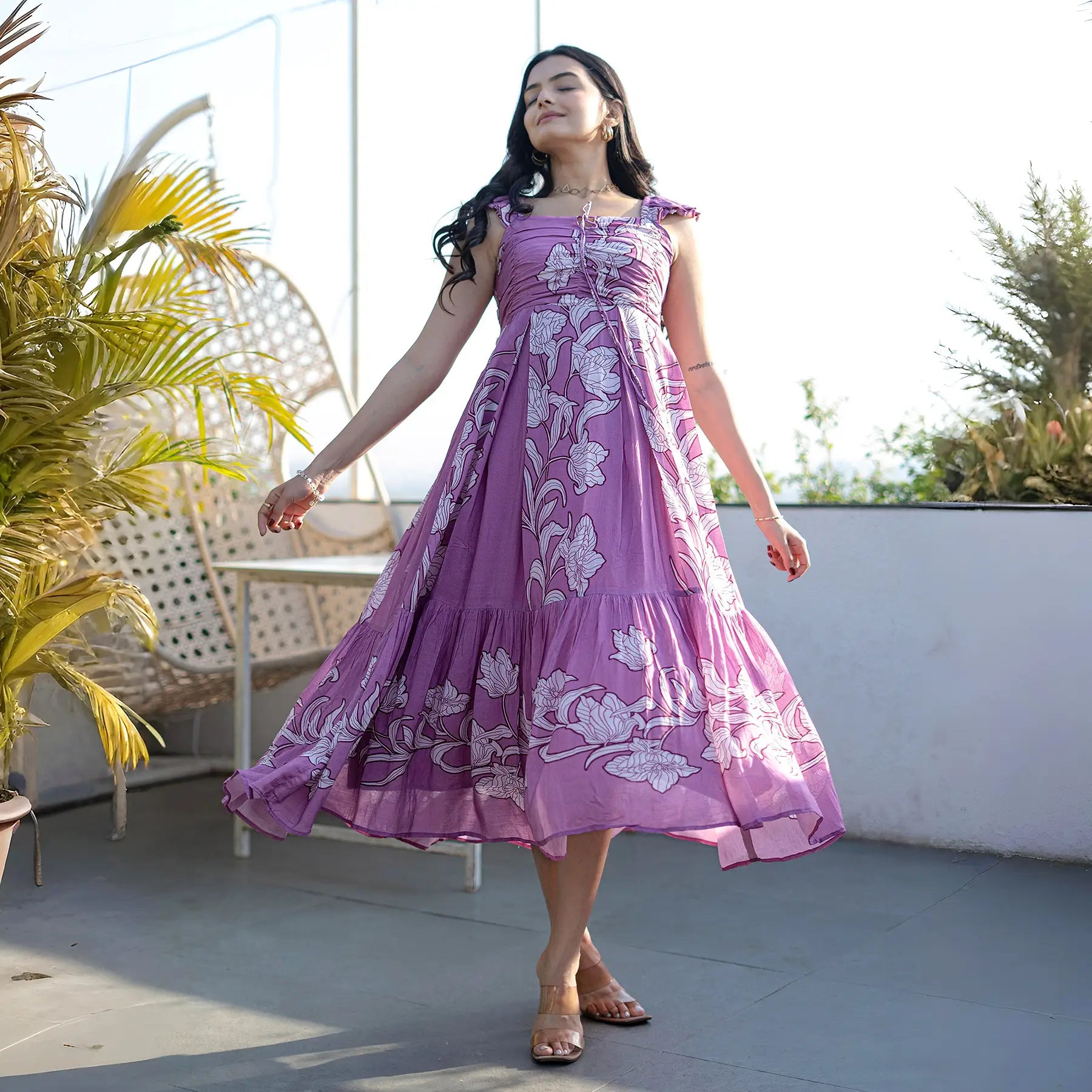 Woman twirling in a lilac floral midi dress with ruffled straps, showing its flowy A-line silhouette.