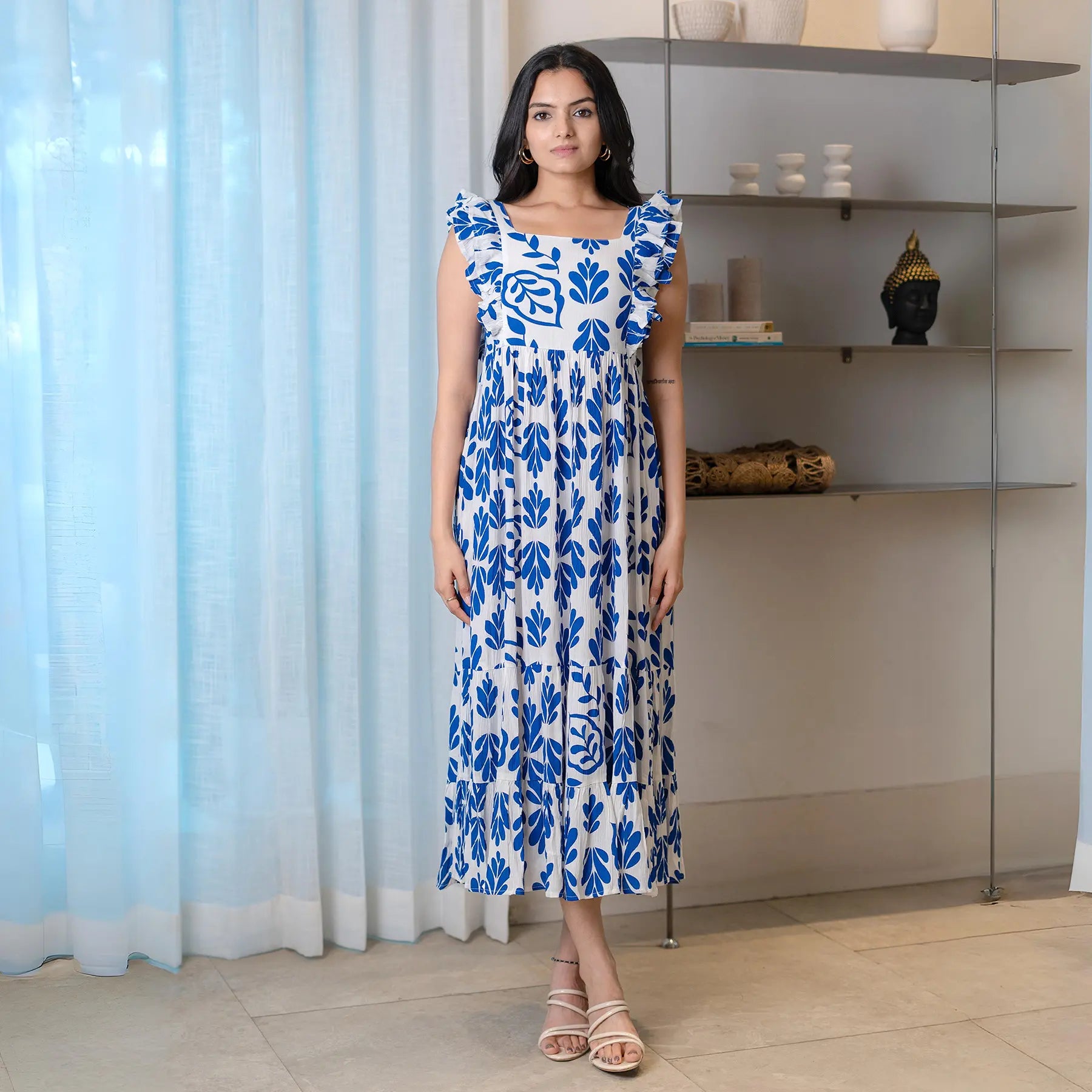 Woman wearing a sleeveless A-line midi dress in leafy blue and white print — chic choice for brunch or summer outings.