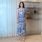 Woman wearing a sleeveless A-line midi dress in leafy blue and white print — chic choice for brunch or summer outings.