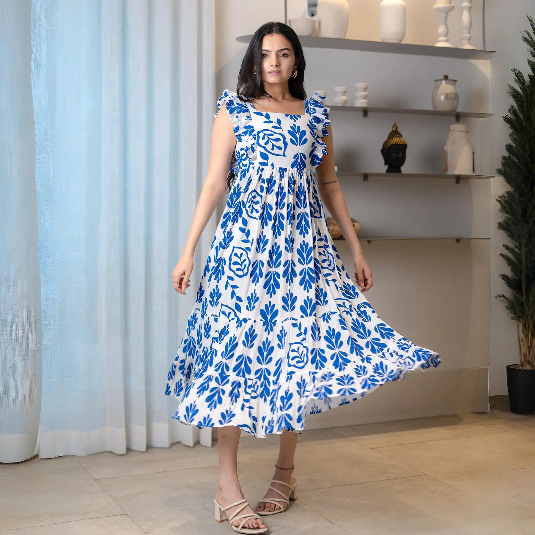 Flowing leafy print midi dress captured mid-twirl, perfect for beach vacations and casual celebrations.