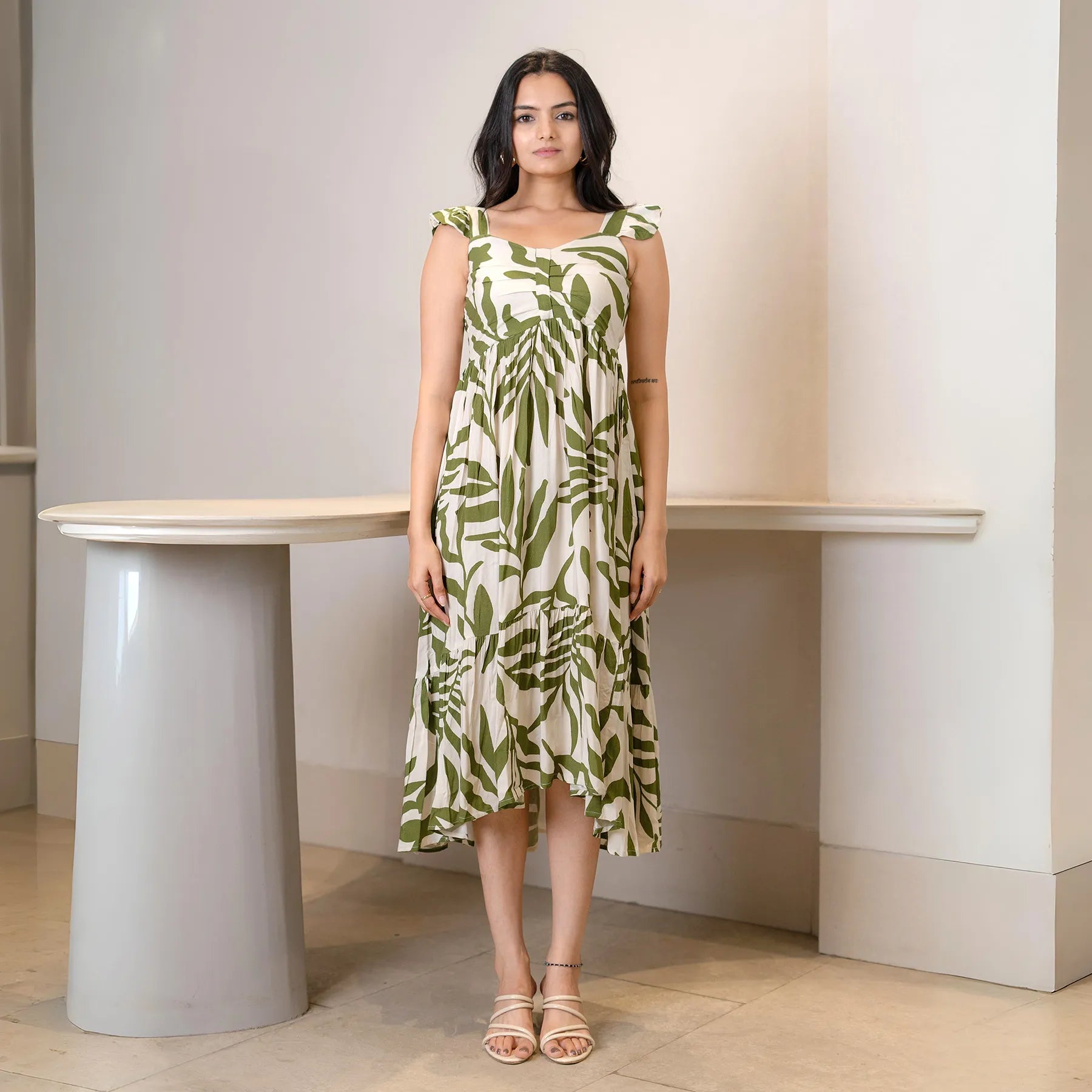 Model in a green leafy print A-line midi dress for women, styled with sleeveless straps — perfect for summer outings.