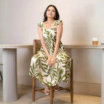 Model seated in a leafy high-low midi dress, giving a relaxed summer vibe suitable for brunch and casual celebrations.