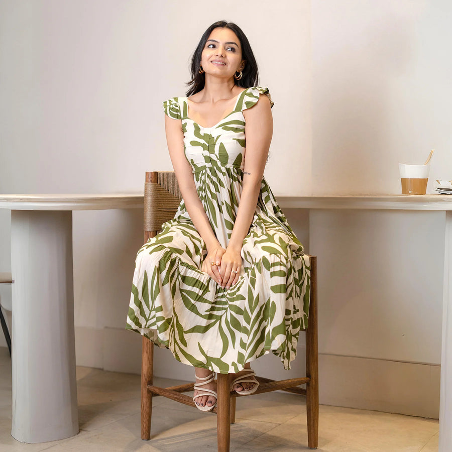 Model seated in a leafy high-low midi dress, giving a relaxed summer vibe suitable for brunch and casual celebrations.