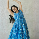 Woman smiling with raised arms in  sleeveless midi dress — breezy and relaxed beach wear dress for women.
