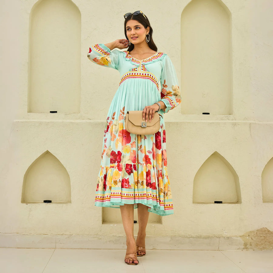 Front pose holding a bag, showing the summer midi dress in pastel color with bright floral print — ideal for summer vacations.