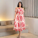 Woman walking in a flowy red print midi dress, a chic pick for vacations and day wear.