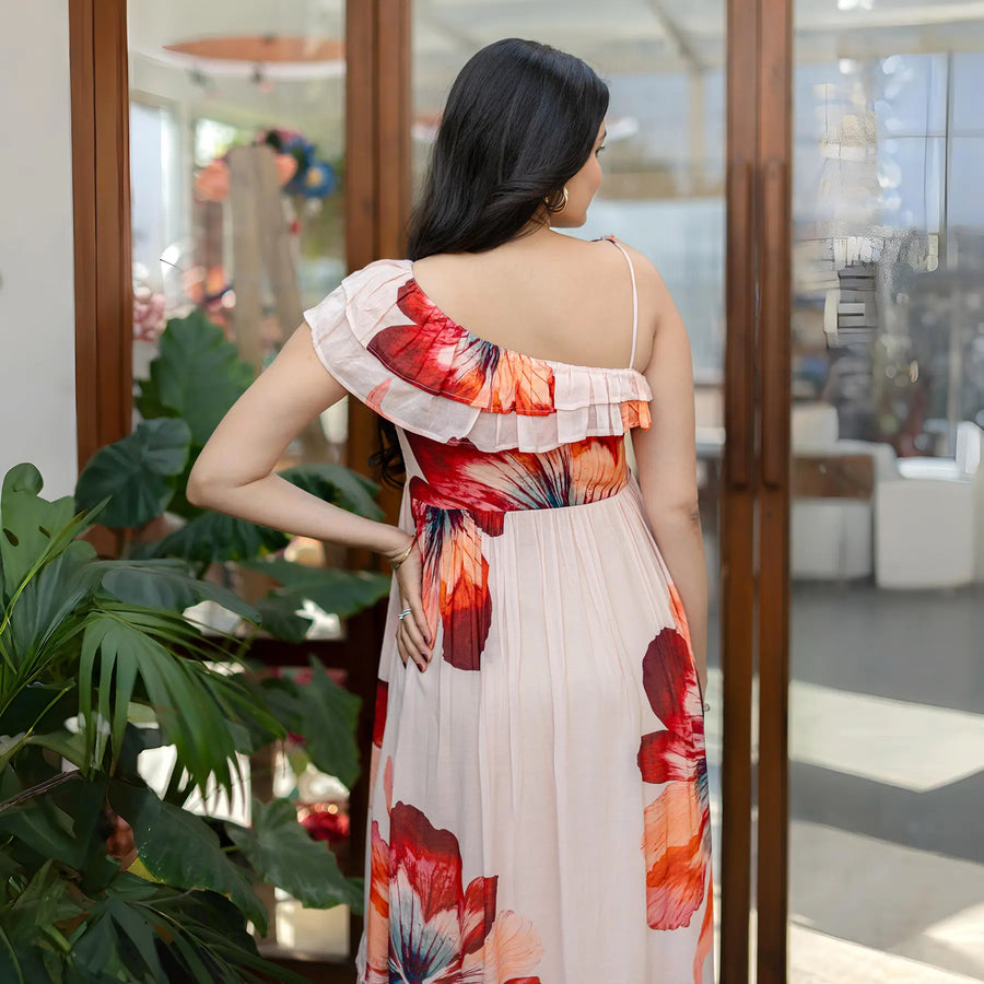 Back view of a sleeveless floral one piece dress, showcasing a ruffled one-shoulder detail.