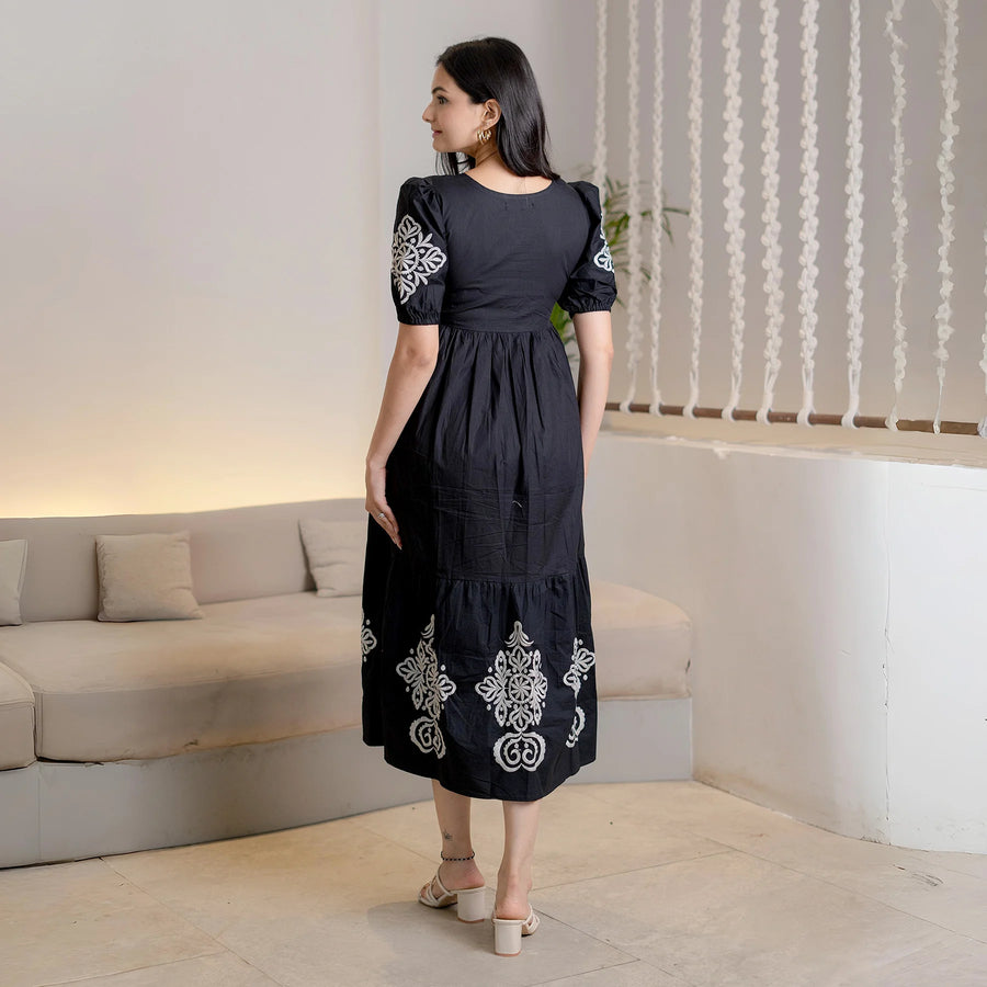 A back pose of this black dress with embroidered flowers and sleeves.