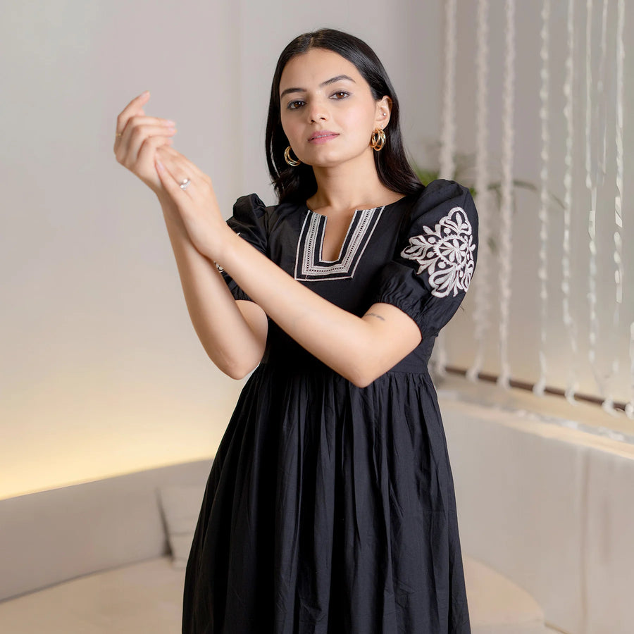 Close-up of Noir Bloom black cotton one-piece maxi dress showing white embroidered details on neckline and sleeves