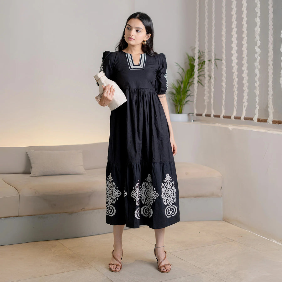 Model pairs Noir Bloom black cotton one-piece maxi dress with a clutch for stylish outings