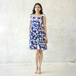 Front view of a blue and white knee length one piece dress, styled as a sleeveless short dress with delicate ruffle straps.