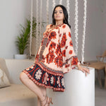 Model sitting gracefully in a frock style short dress for women, styled with scarlet floral patterns for summer outings
