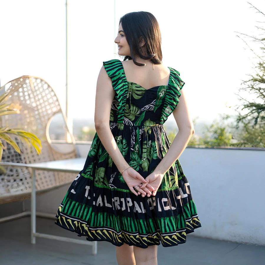 Back view of a tropical green short one piece dress, knee length with airy summer silhouette