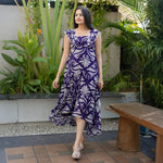 Woman wearing sleeveless one-piece maxi dress with floral print, captured in side view.