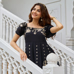 Close-up of woman smiling in a modern black dress with gold floral detail and short puffed sleeves