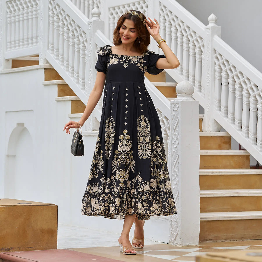 Woman walking outdoors in a black A-line midi dress with gold floral print and puff sleeves