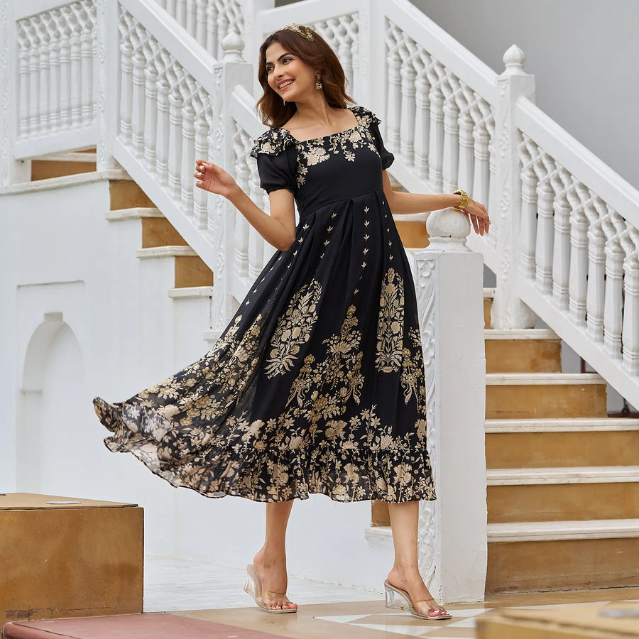 Model in black A-line midi dress resting her arm on a pillar, smiling softly